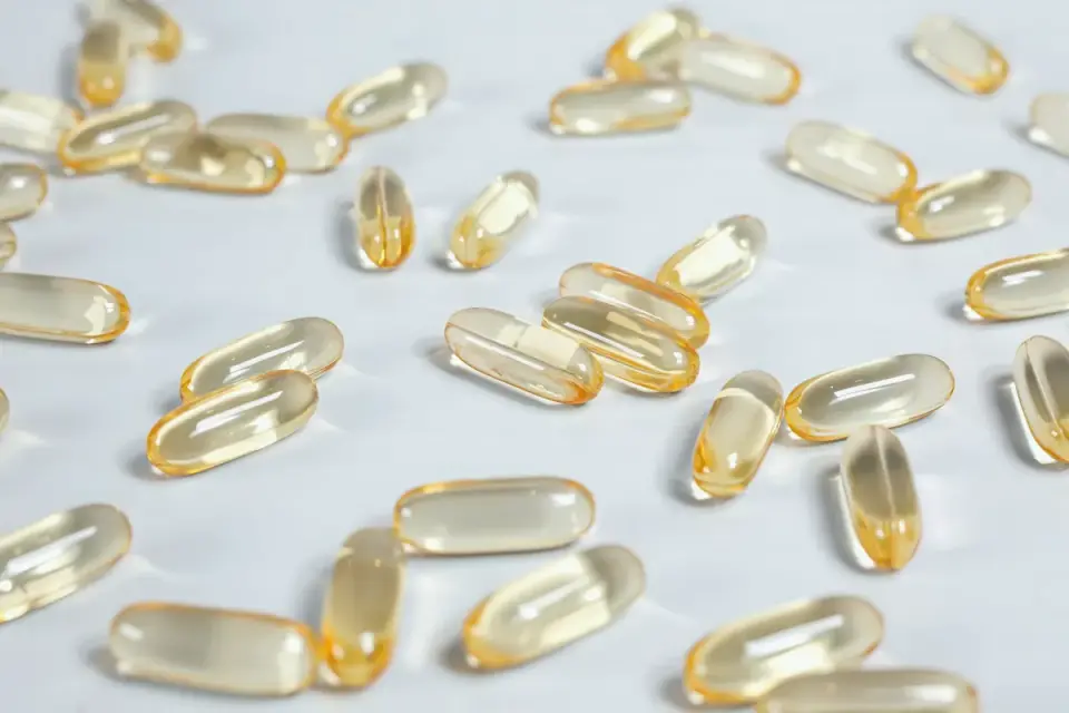 A bottle of fish oil supplement capsules beside a dog&#x27;s food bowl