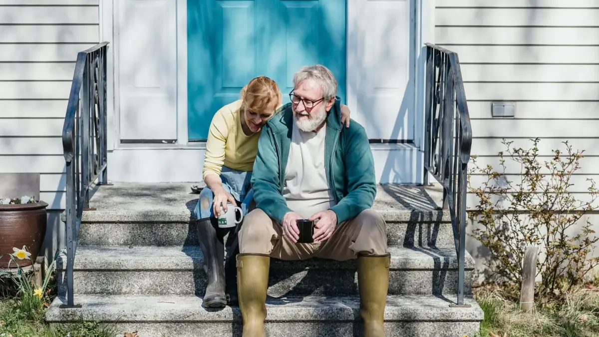 A senior dog standing at the bottom of a short flight of porch steps