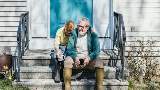 A senior dog standing at the bottom of a short flight of porch steps