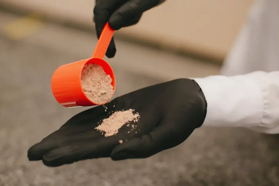 A supplement bottle and scoop on a kitchen counter next to a dog bowl