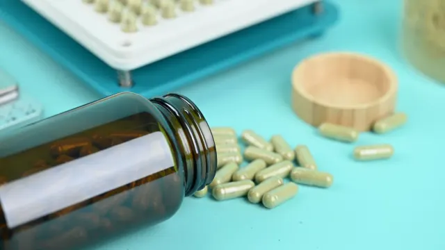 A supplement capsule bottle sitting on a kitchen counter next to a small dog looking up