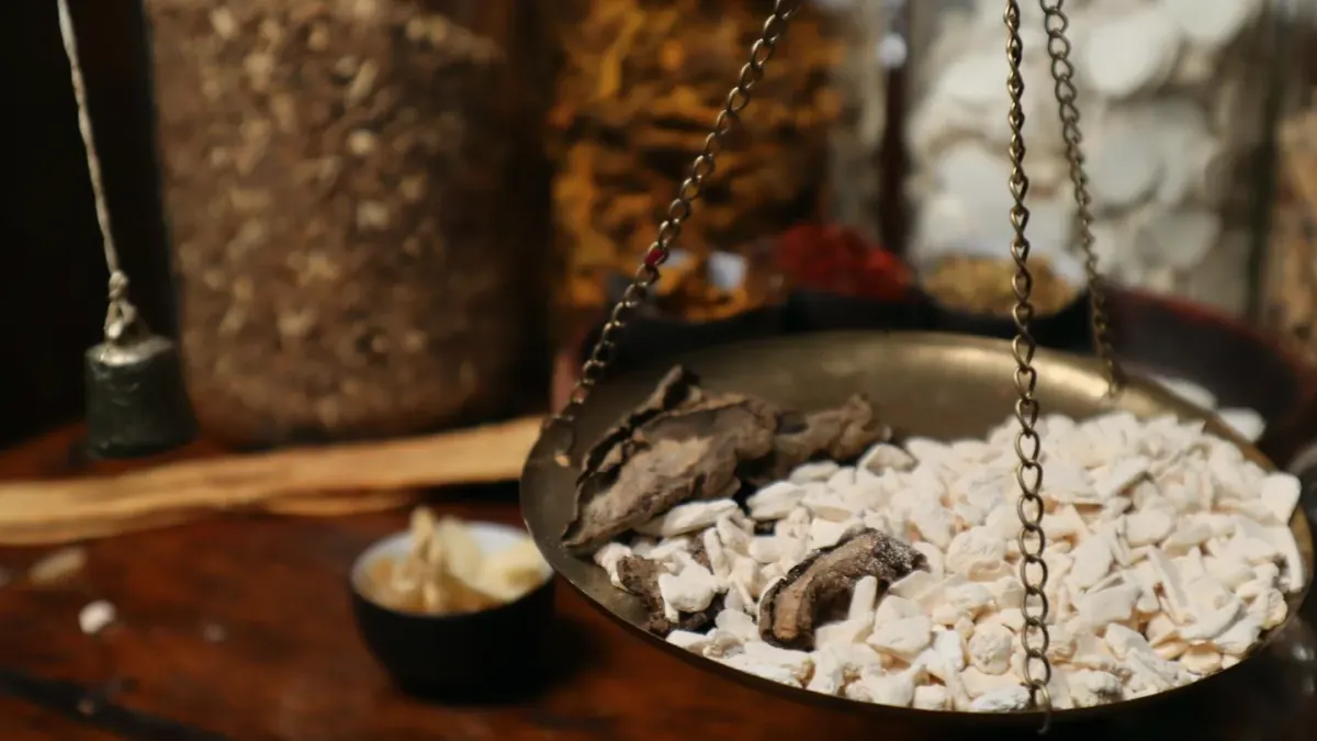 Dried ashwagandha root pieces and a small pile of ground powder on a wooden surface