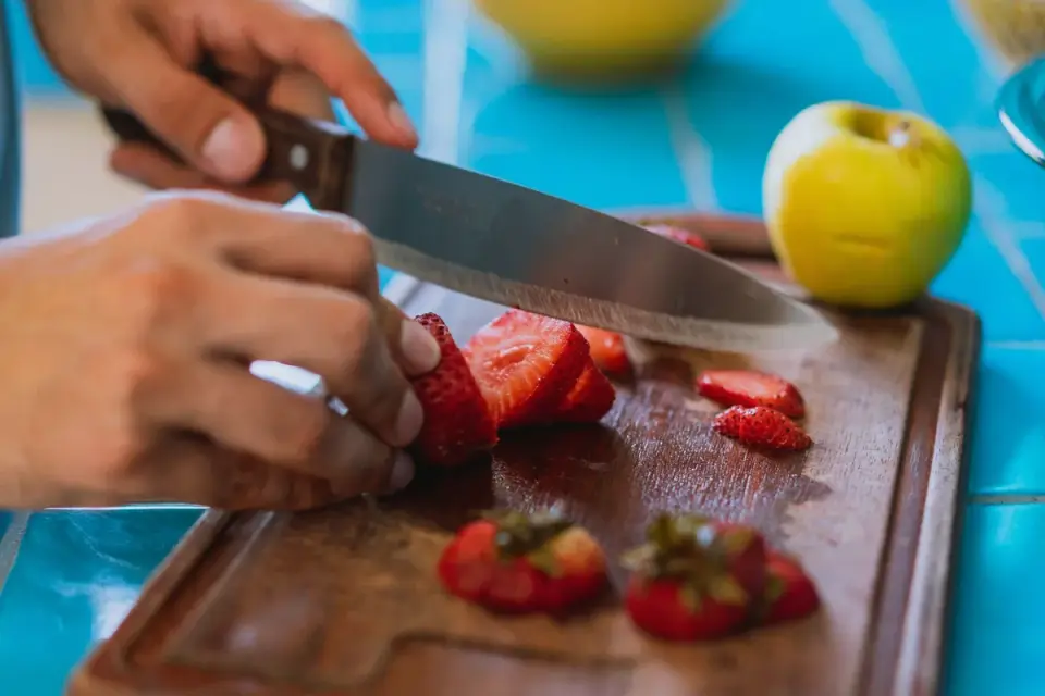 Hands coring a red apple on a cutting board before slicing it for a dog