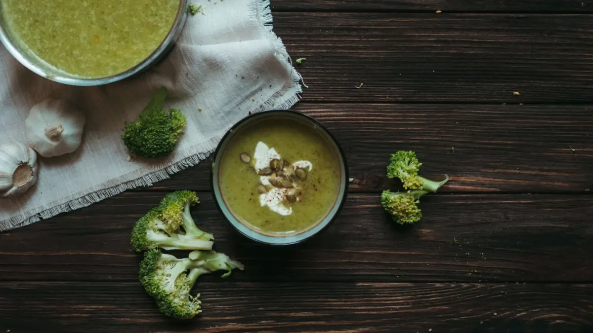 Small steamed broccoli florets set beside a stainless bowl of dog kibble