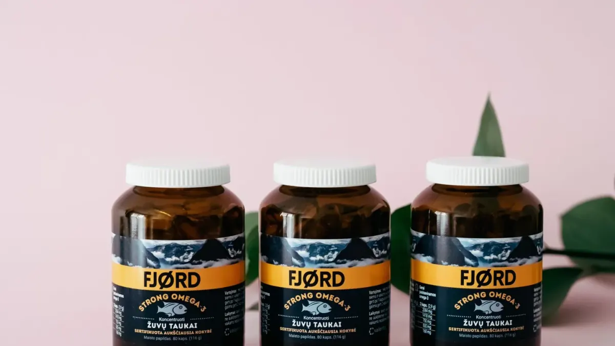 Two supplement bottles, one amber fish oil and one flaxseed oil, standing side by side on a counter